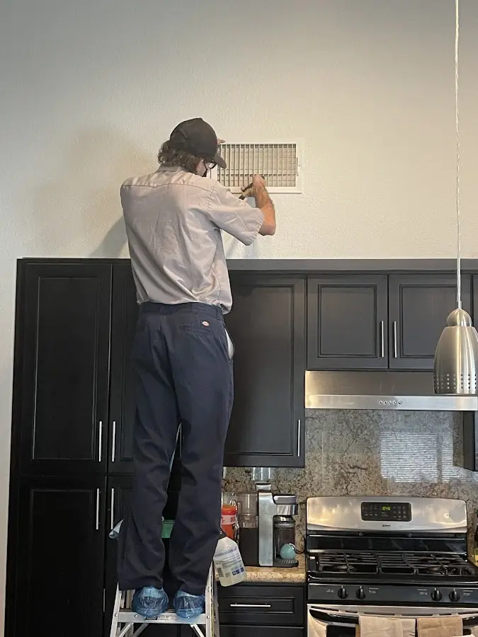 Technician inspecting an air vent during HVAC service in Dundee